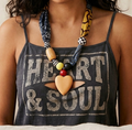 Person wearing a tank top with 'Heart & Soul' text and a colorful scarf necklace.