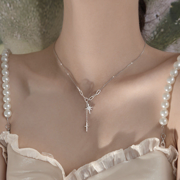 Dual north star lariat necklace on white surface with shadow detail