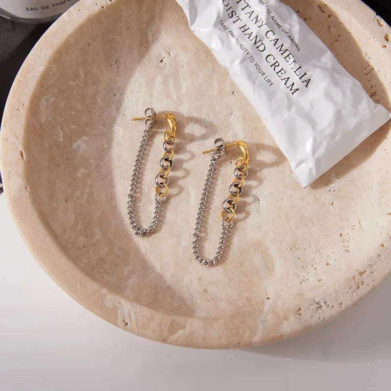 Two-tone chain drop earrings on black leather bag