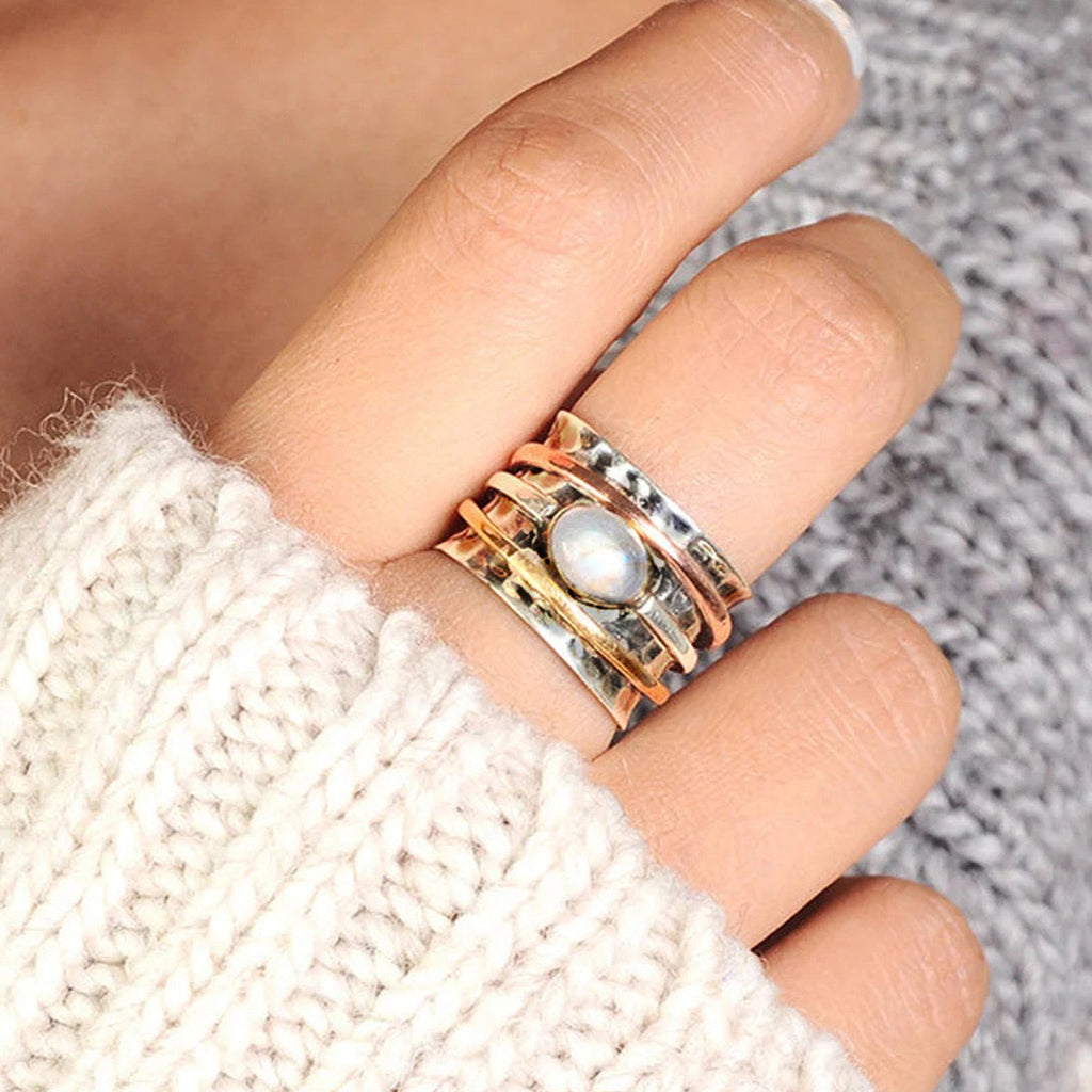 Moonstone spinner ring worn on model finger with cream knit sweater