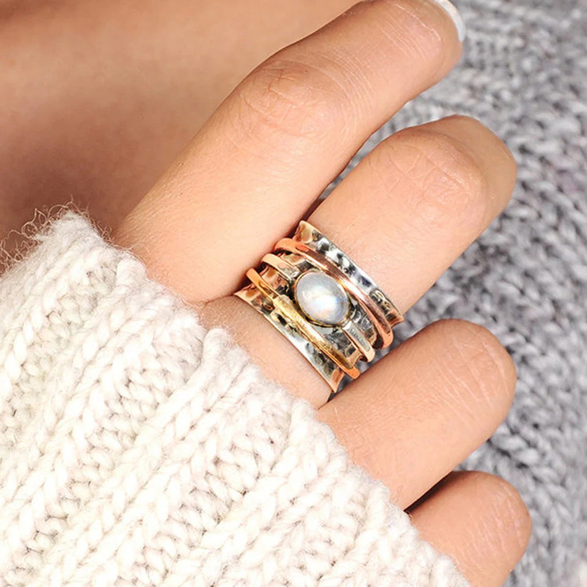 Moonstone spinner ring worn on model finger with cream knit sweater