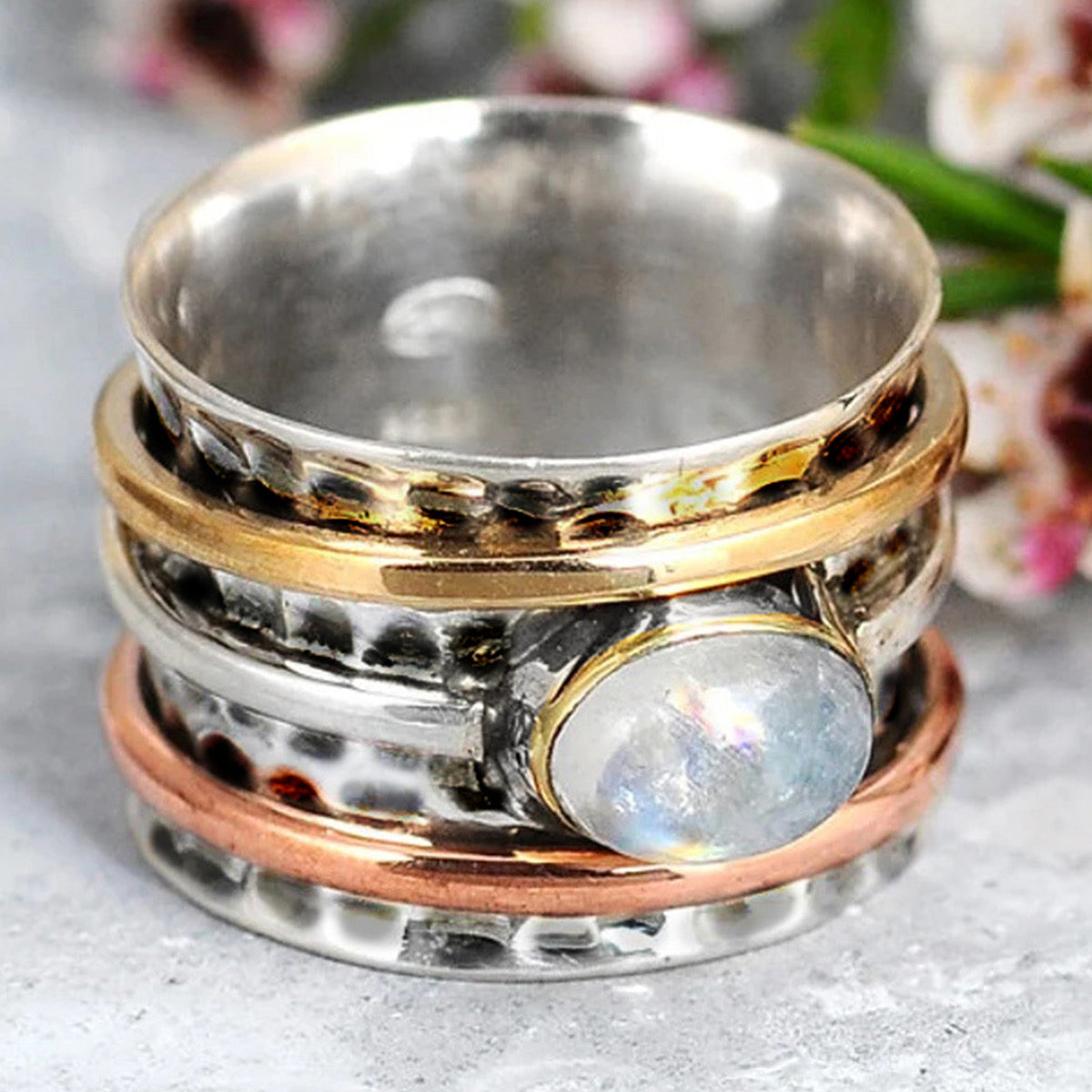 Moonstone tri-tone spinner ring close up detail on grey marble
