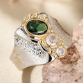 Emerald green stone wide-band ring on purple velvet
